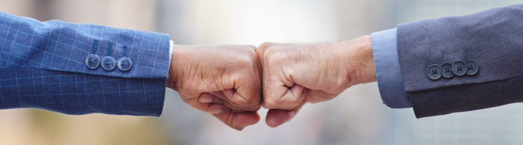 two fists of two men in suits colliding